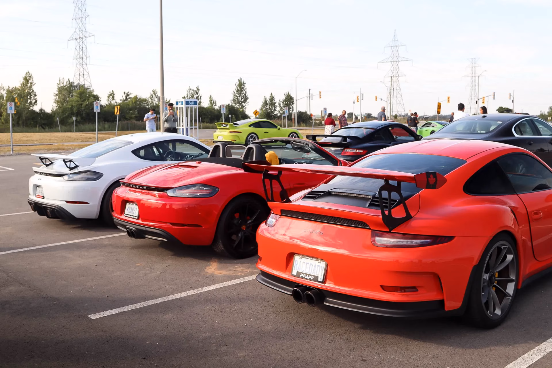 White and red Porsches with rear wings parked side by side at an outdoor meet
