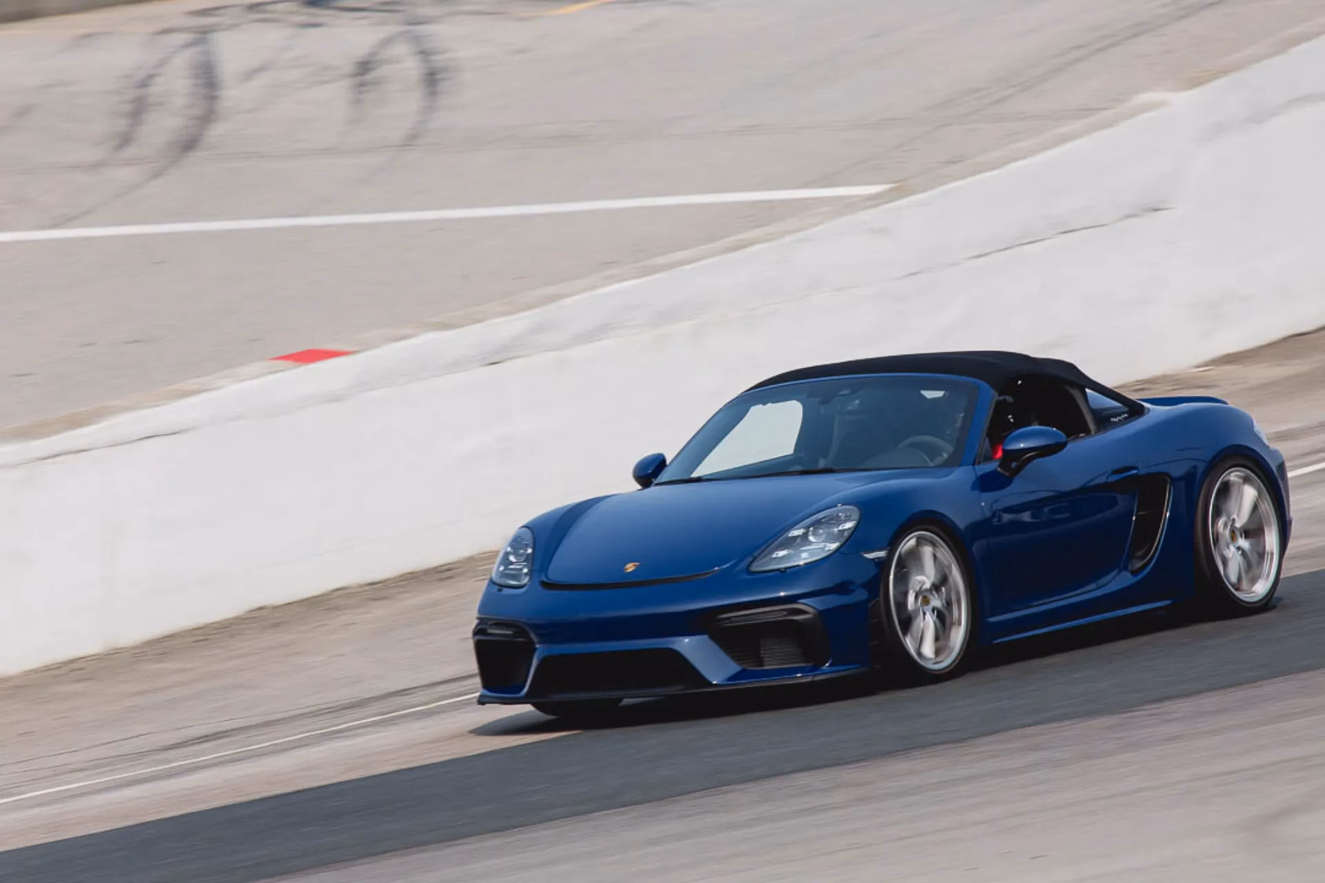 A blue Porsche 718 roadster on track