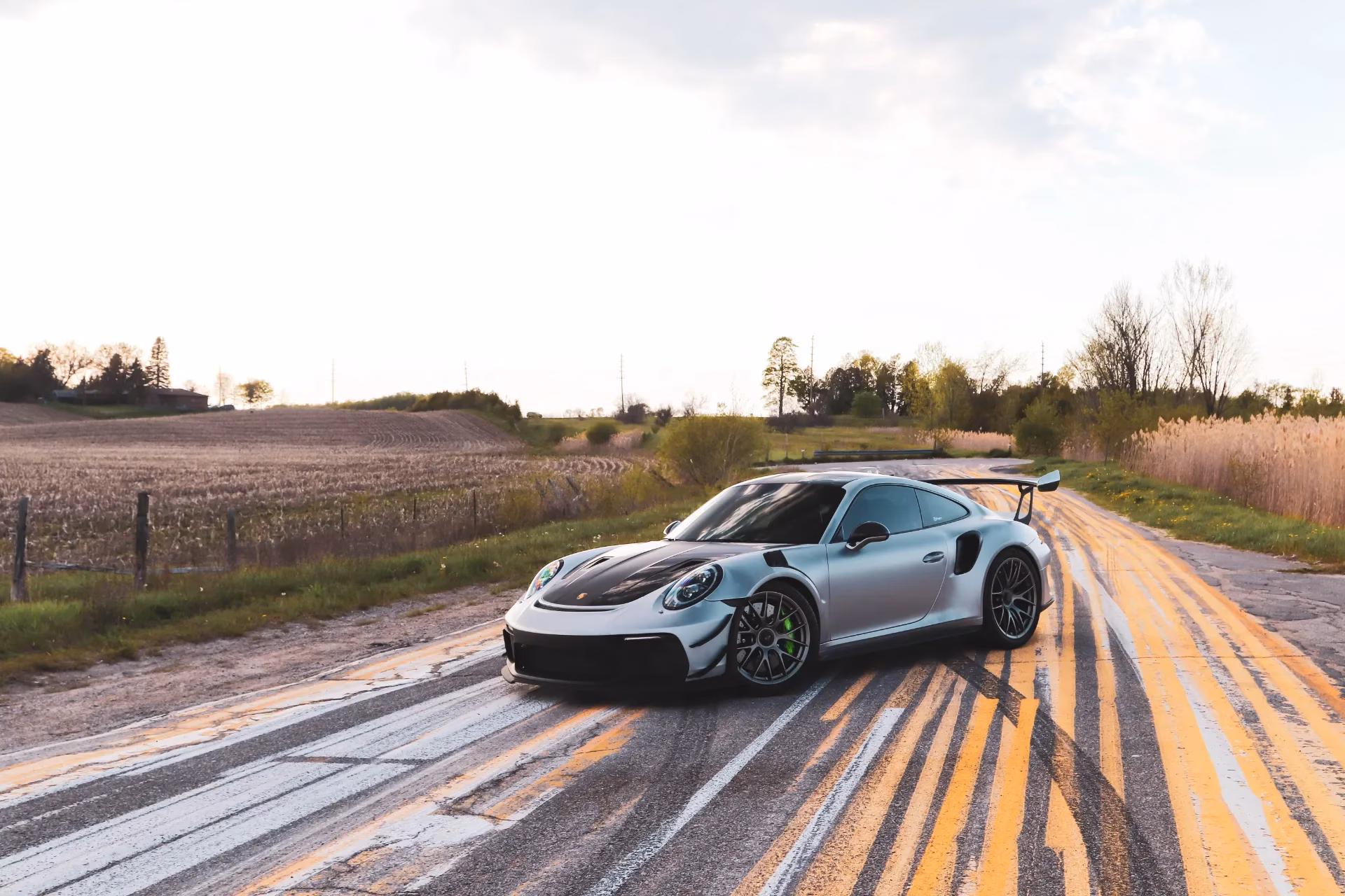 A silver Porsche 911 GT3 RS parked on a rural road at dusk