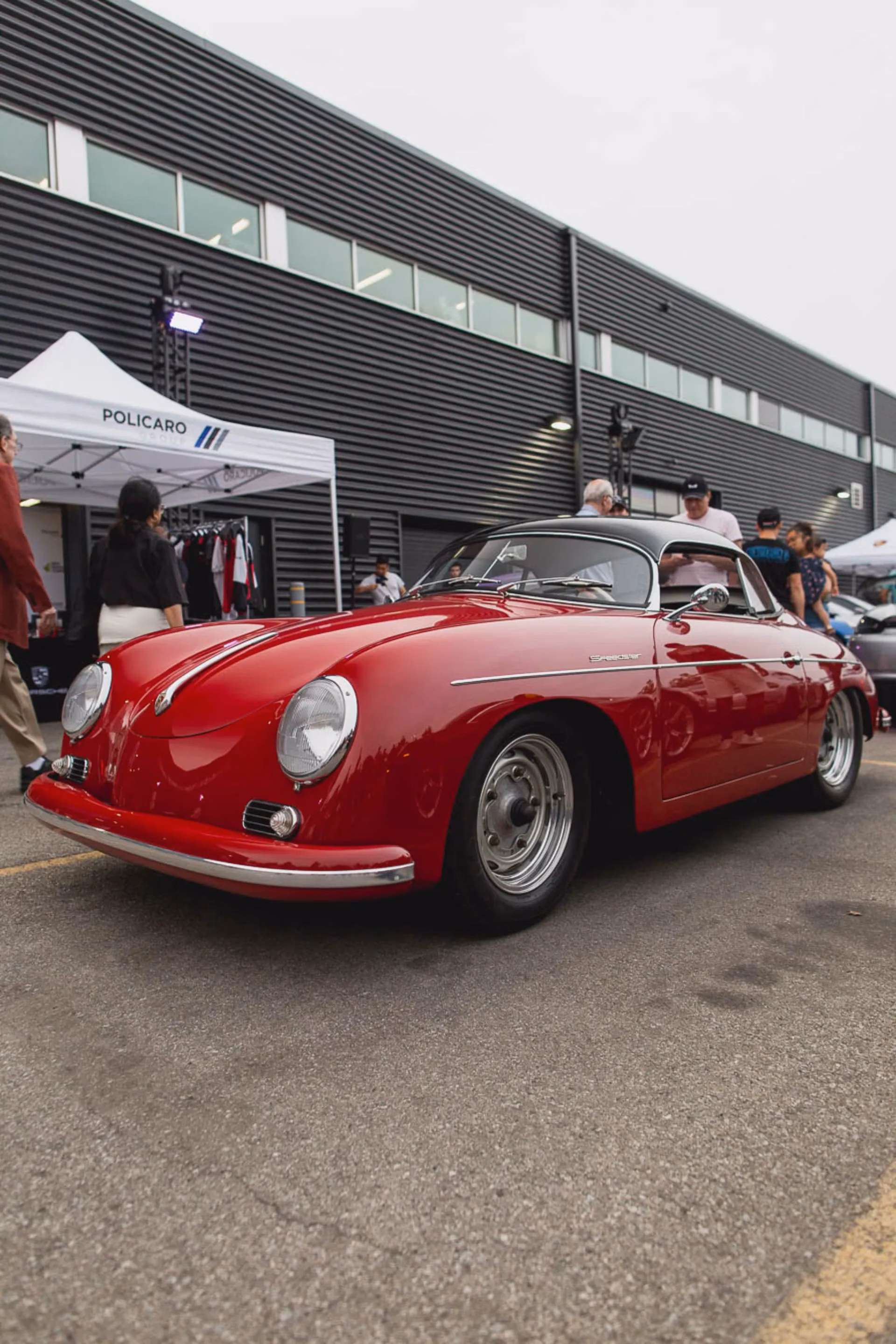 A red Porsche 356 parked at an outdoor meet, a Policaro tent behind it