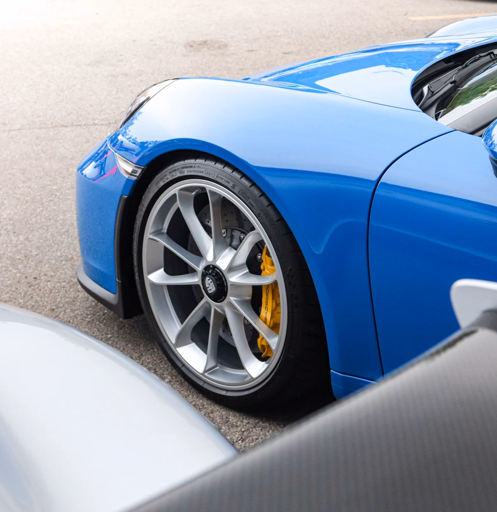 Close-up of a blue Porsche 911's front wheel and yellow brake caliper