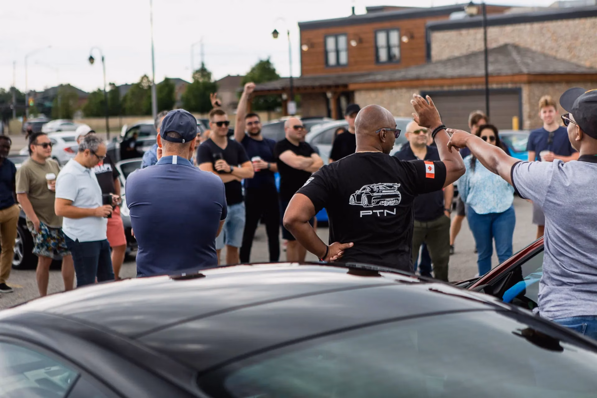 Members gathered in a parking lot for a driver's briefing, one wearing a PTN shirt