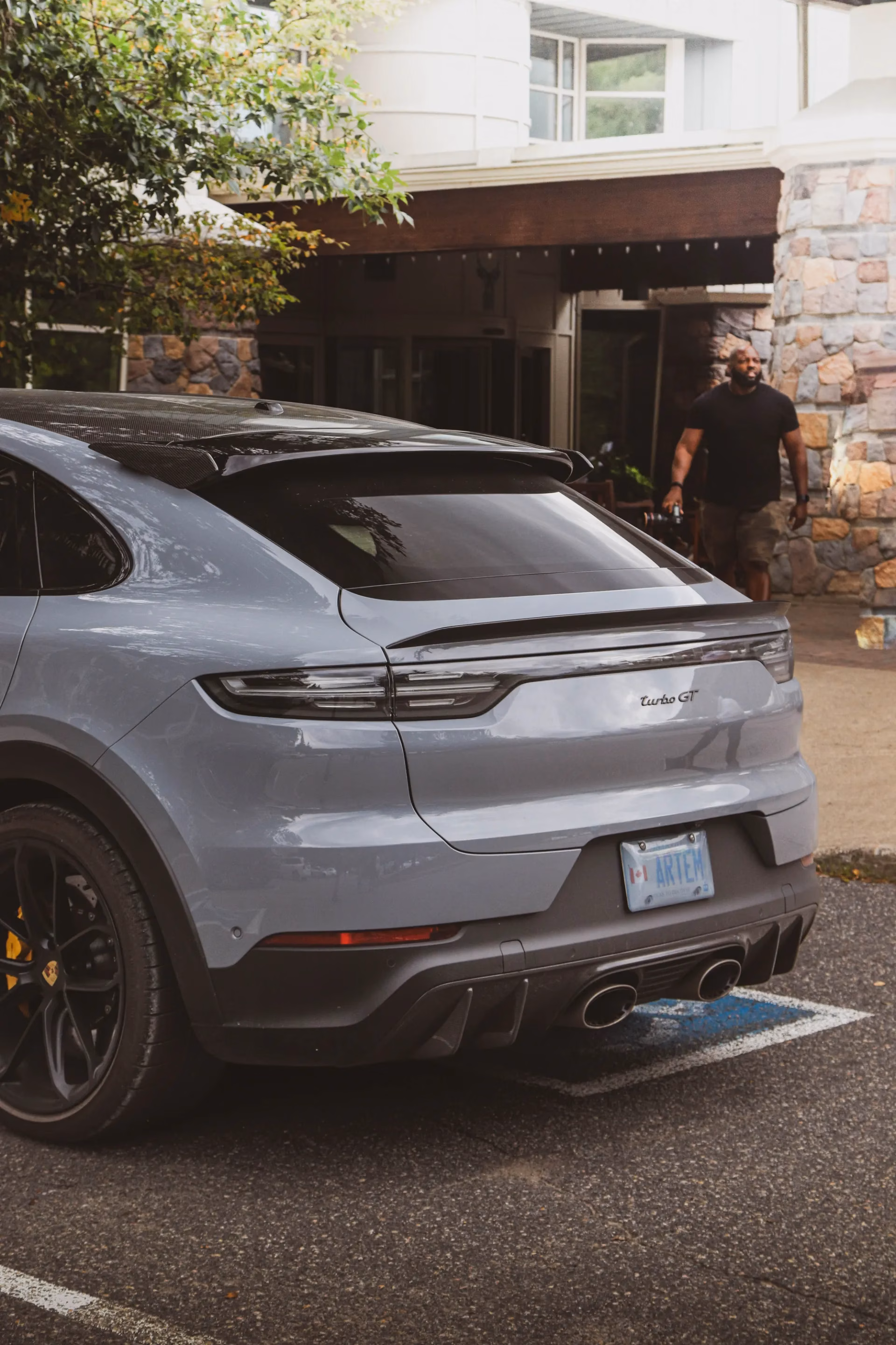 A grey Porsche Cayenne Turbo GT parked at the entrance of a stone and timber lodge