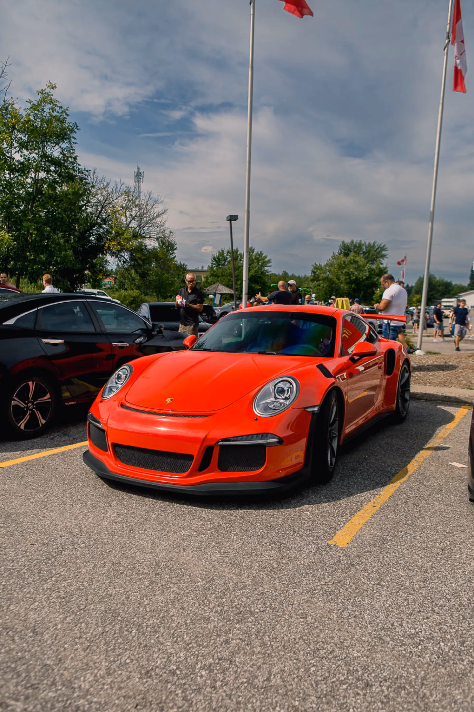 A red Porsche 911 GT3 RS parked beneath Canadian flags at an outdoor meet