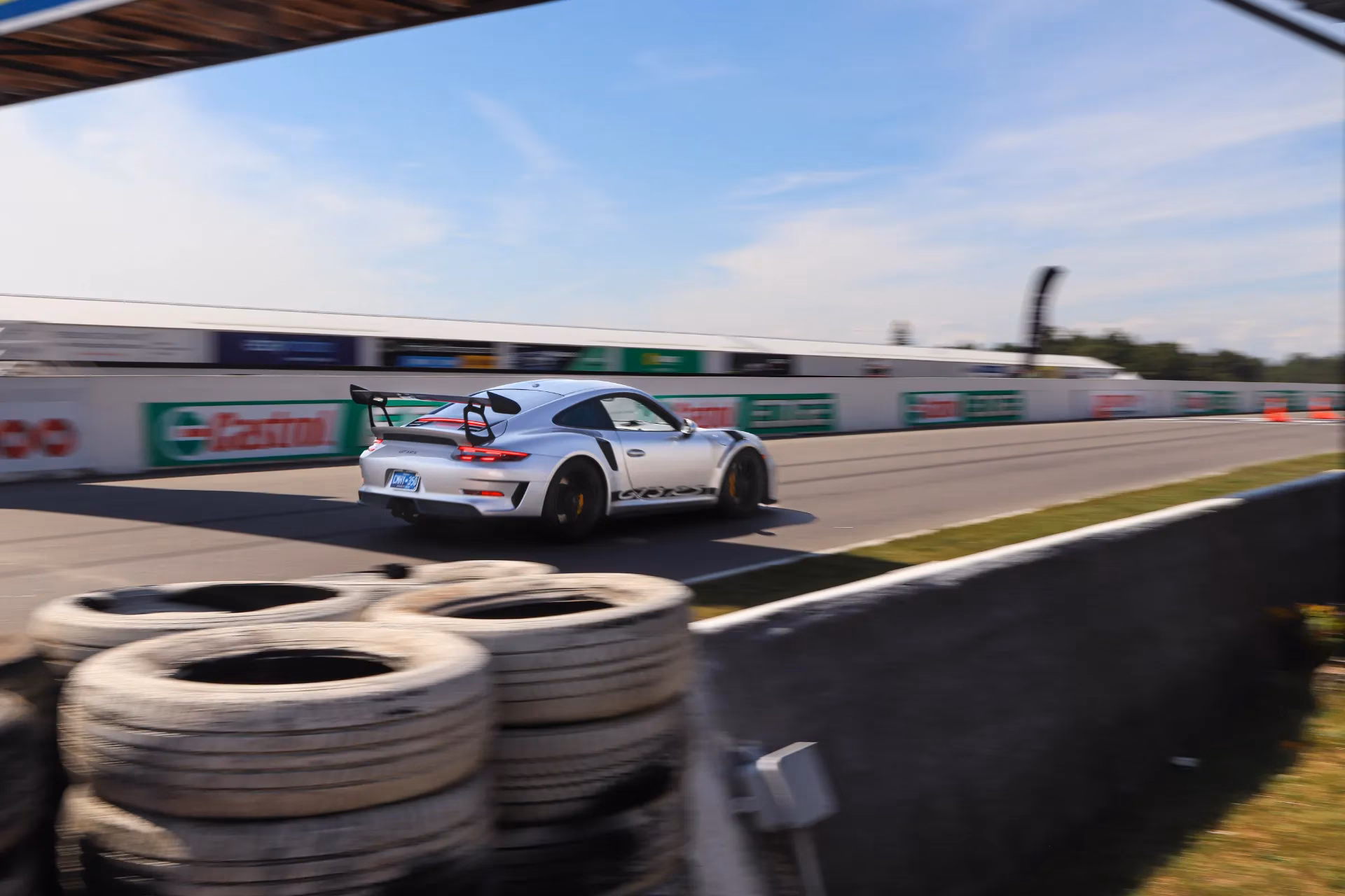 A white Porsche 911 on track passing tyre stacks and trackside barriers