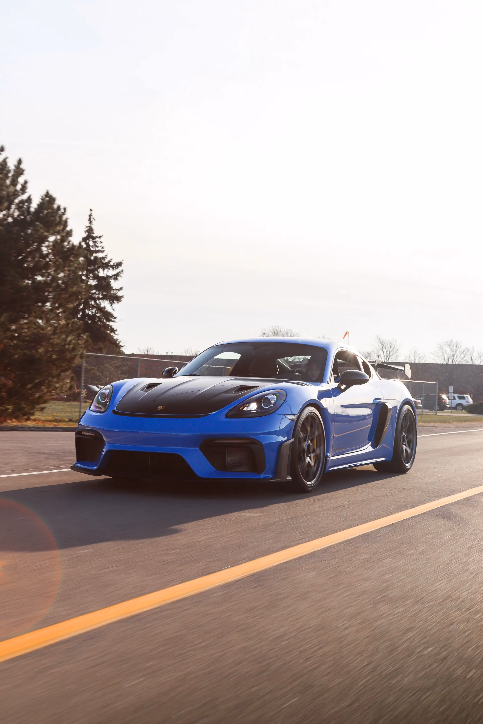 A blue Porsche Cayman GT4 RS with a carbon hood on the road