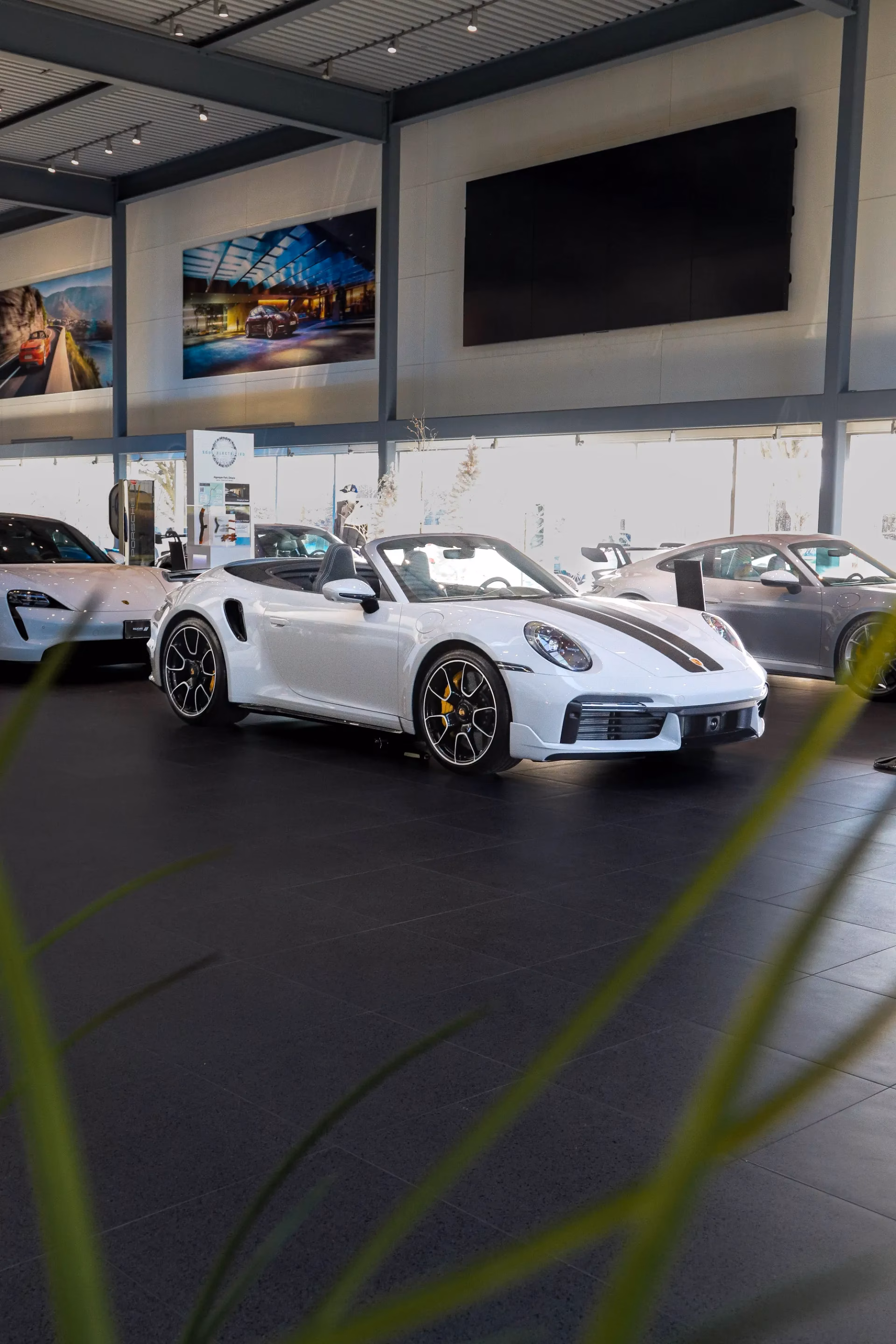 A white Porsche 911 cabriolet on a showroom floor