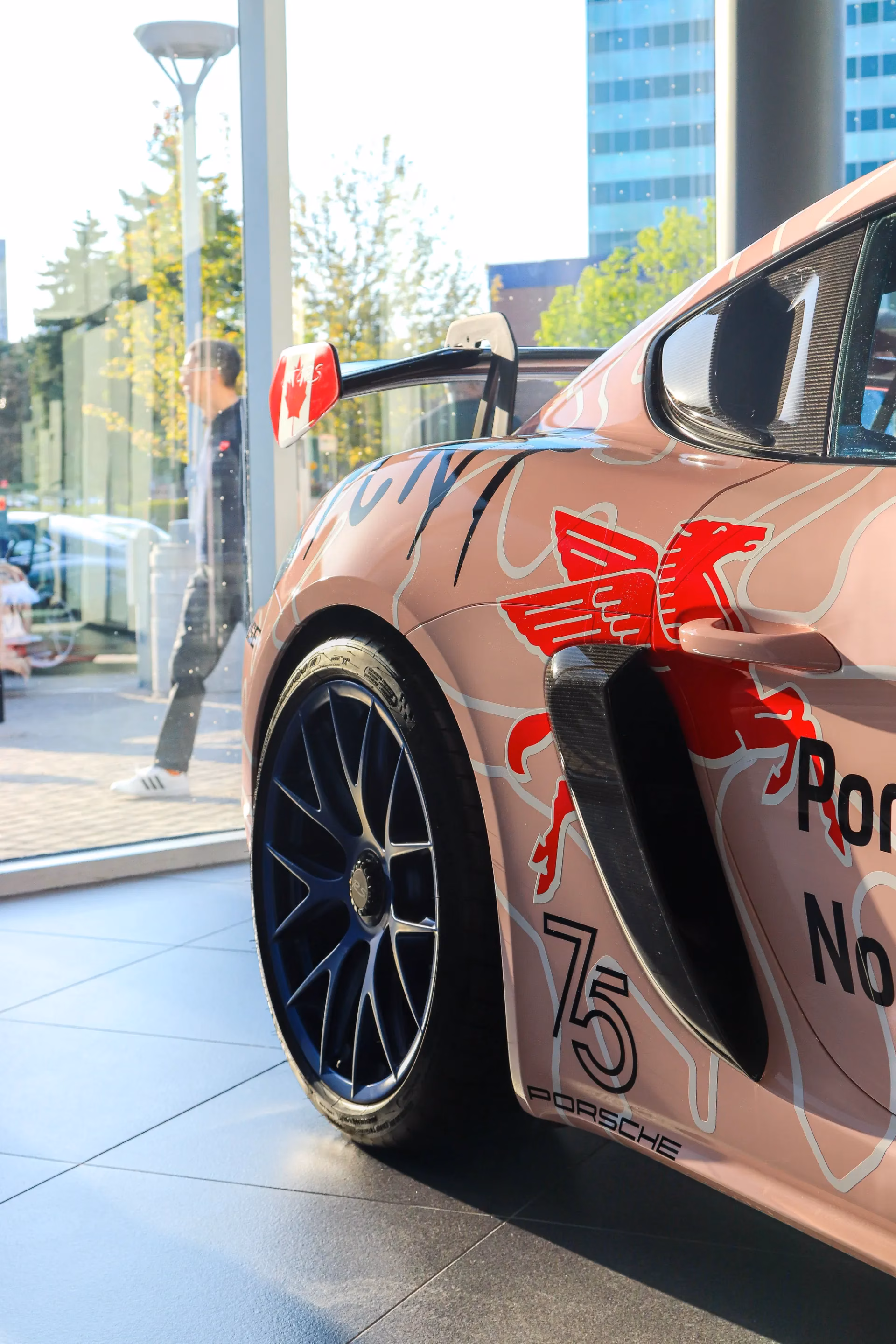 The pink race-liveried Porsche Cayman's flank, showing its pig graphic and 75 roundel