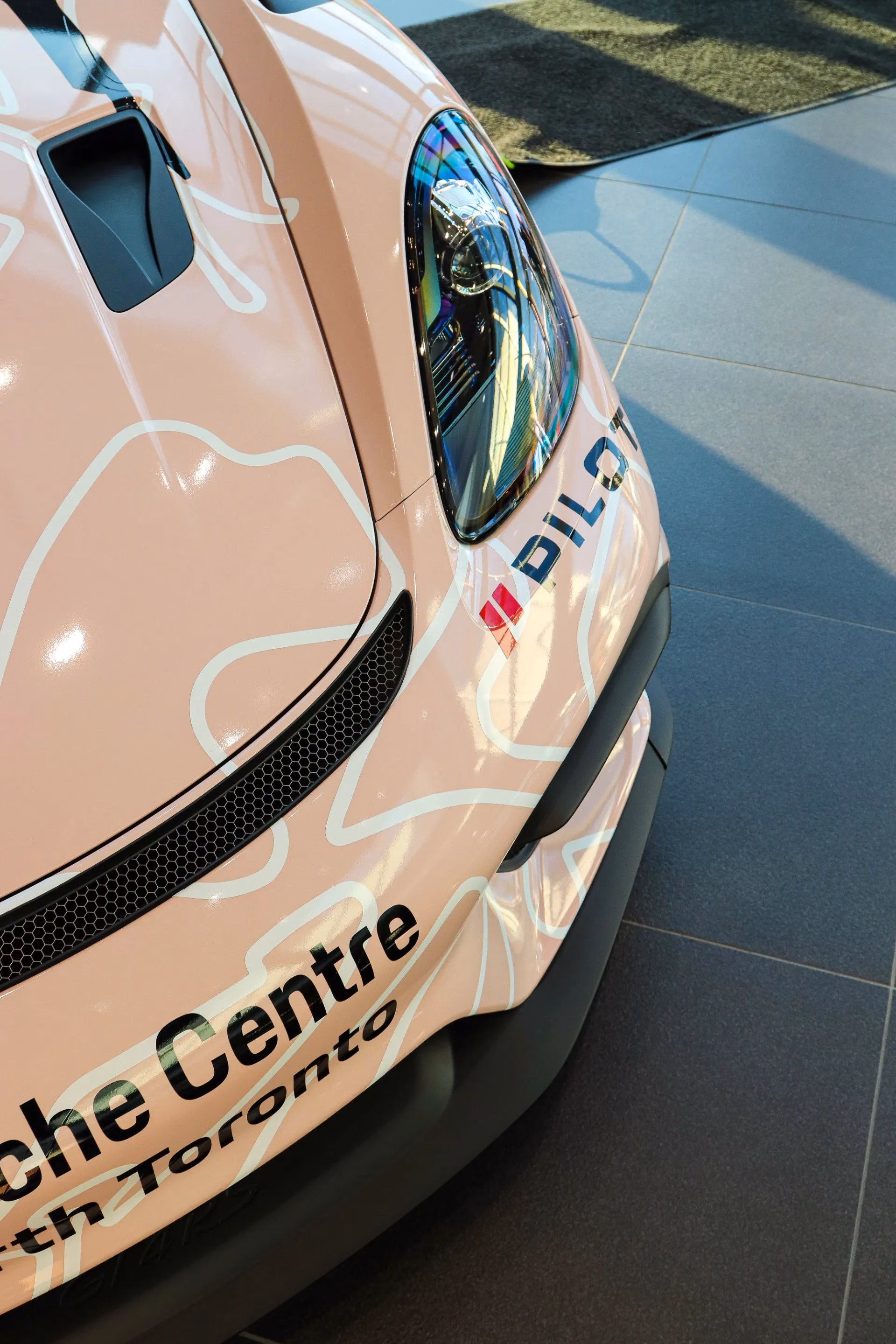 Close-up of the pink race-liveried Porsche Cayman's front corner and Porsche Centre North Toronto lettering