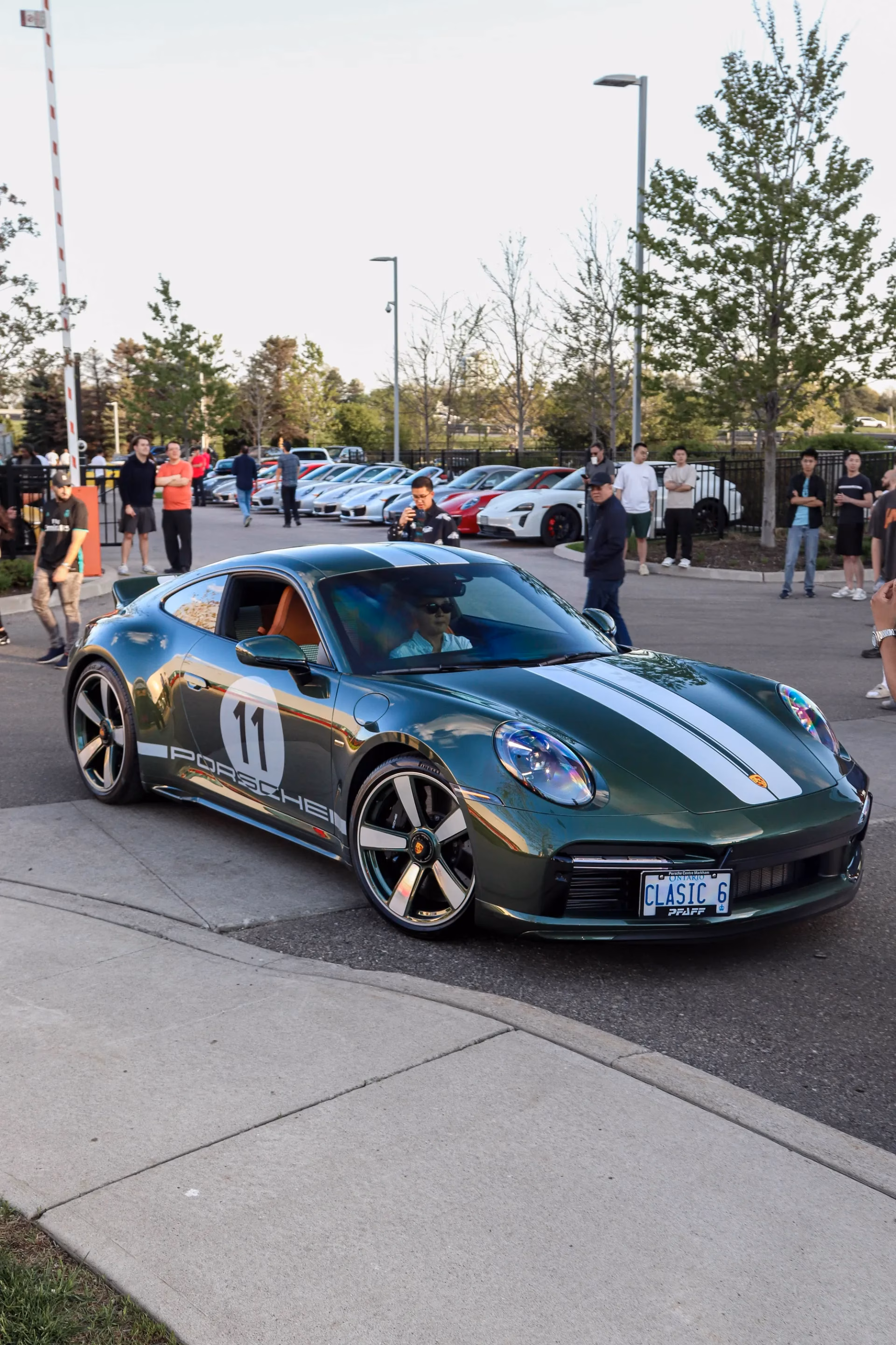 A dark green Porsche 911 Sport Classic with silver stripes and a number 11 roundel at an evening meet