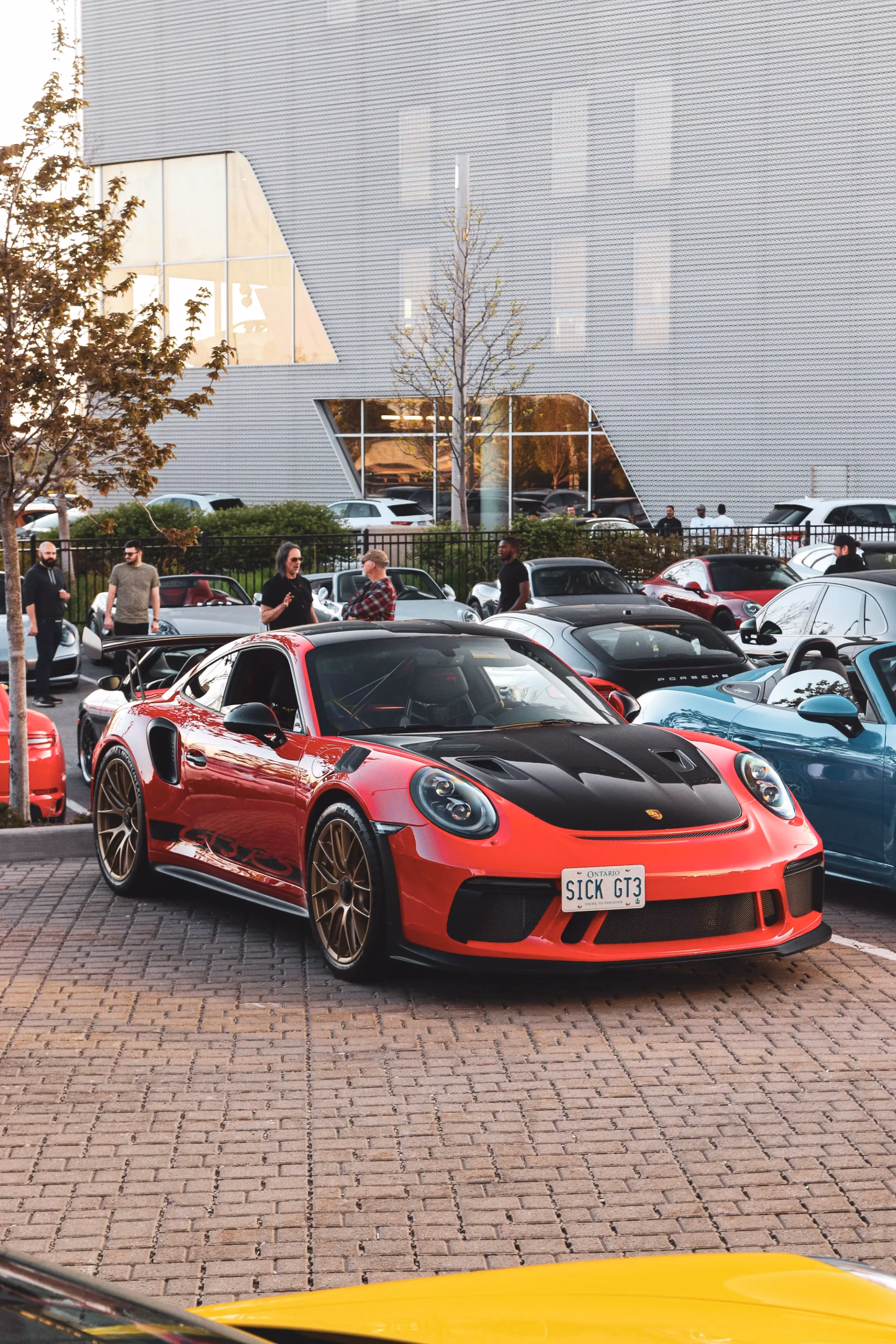 A red Porsche 911 GT3 RS with bronze wheels and a SICK GT3 licence plate at an evening meet