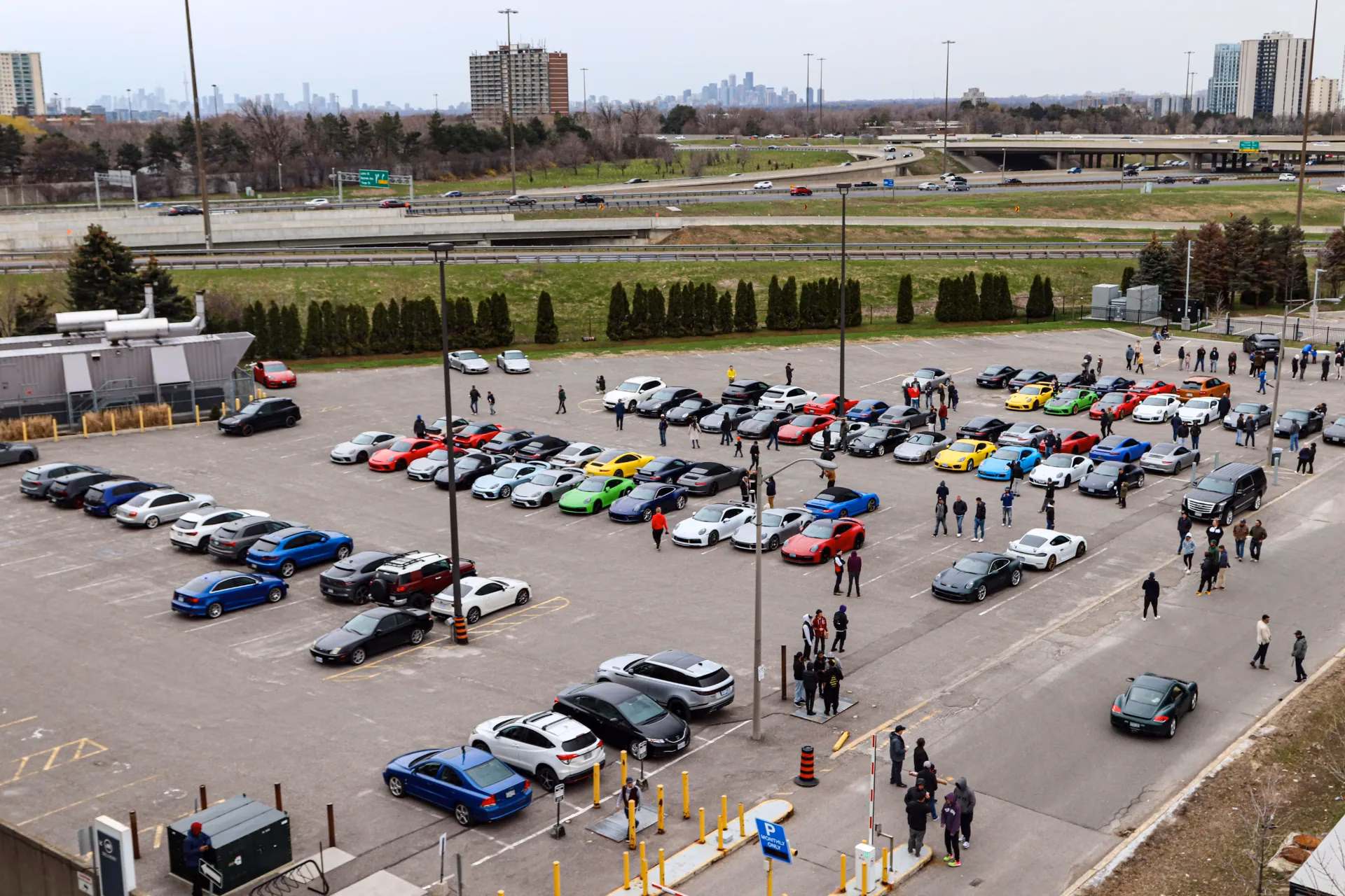 Elevated view of a club gathering filling a parking lot, with the Toronto skyline on the horizon