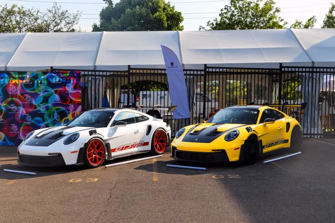 A white and a yellow Porsche 911 GT3 RS parked side by side outside an event marquee