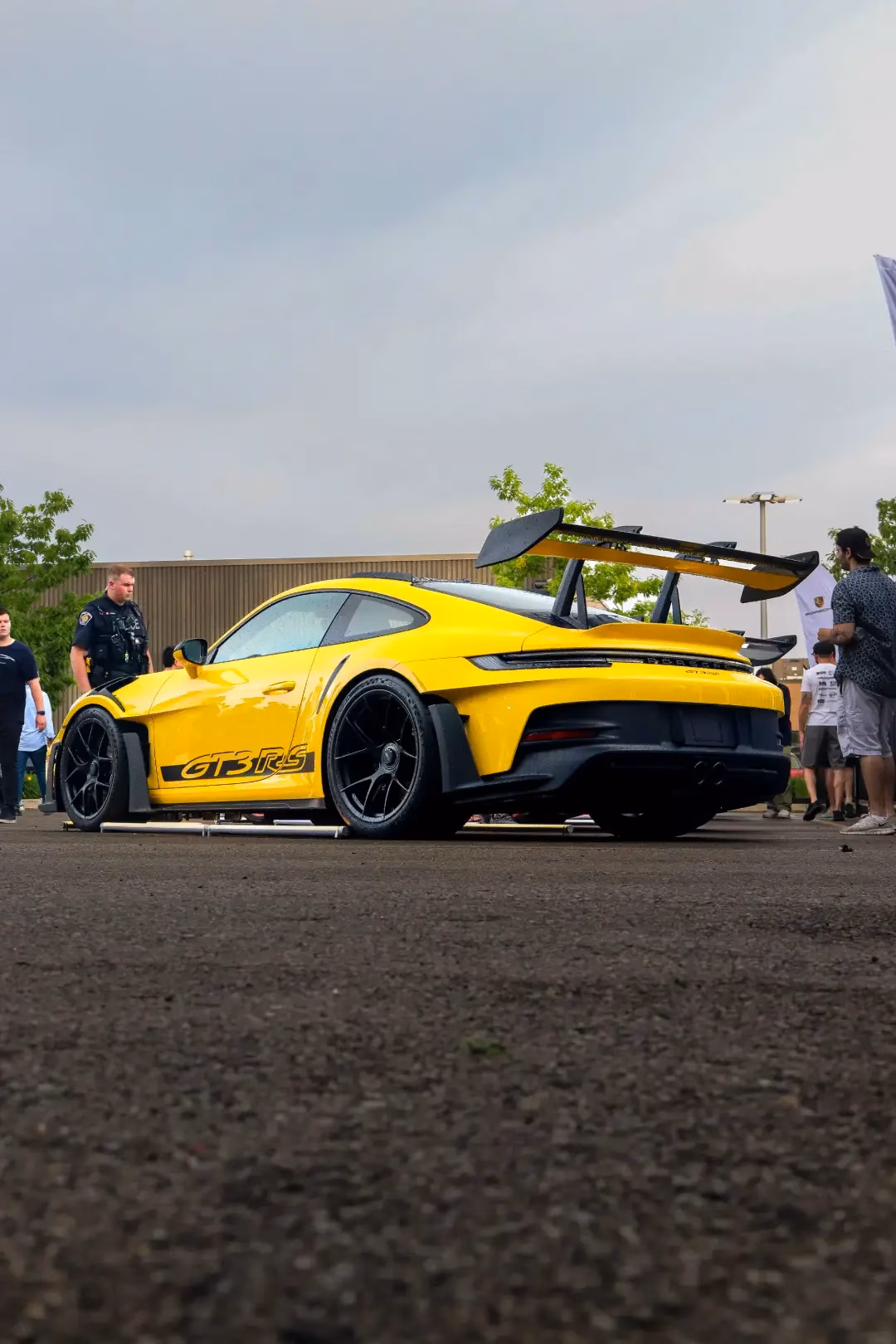 A yellow Porsche 911 GT3 RS with a swan-neck rear wing at an outdoor meet