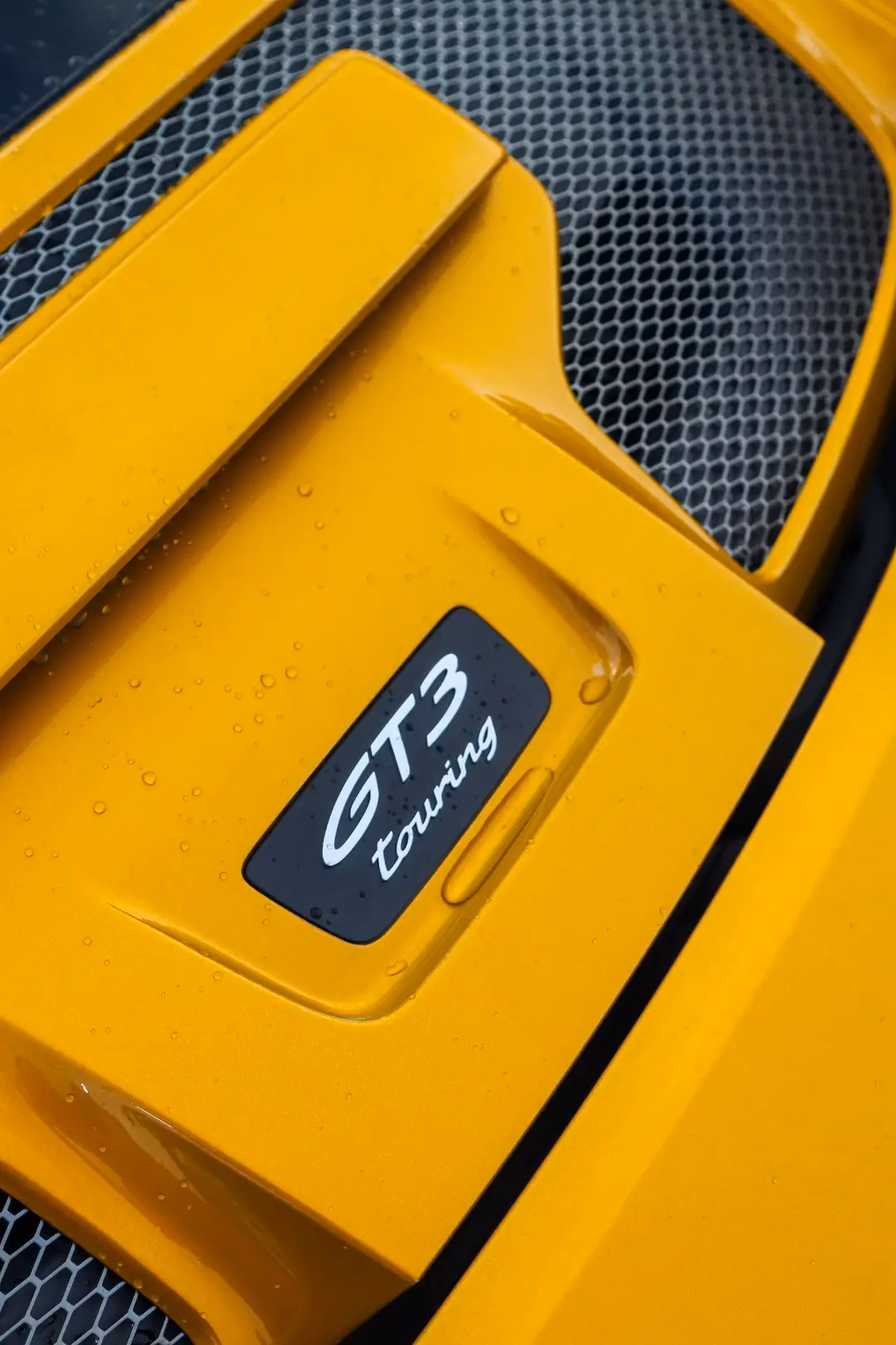 Close-up of the GT3 Touring badge on the engine lid of a yellow Porsche