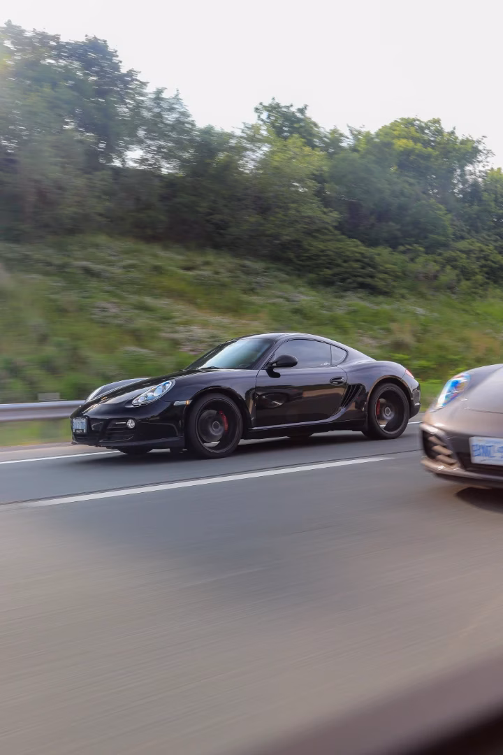 A black Porsche Cayman at speed on the highway