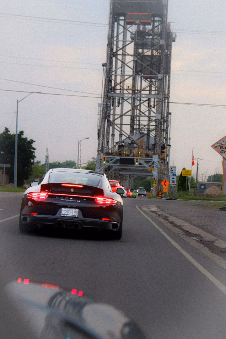 A black Porsche 911 approaching a raised lift bridge