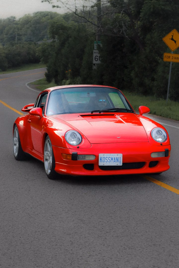 A red classic Porsche 911 on a country road