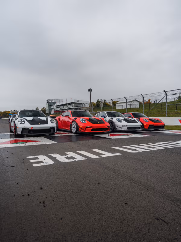 Four Porsche 911s parked on a start line marked with Dunlop Tire lettering