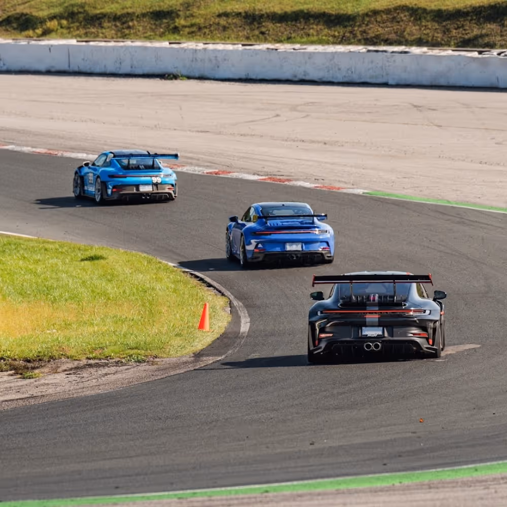 Three Porsches cornering in line on track